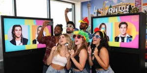 Friends enjoying a photo booth to find their celebrity look alike with fun props and bright atmosphere.